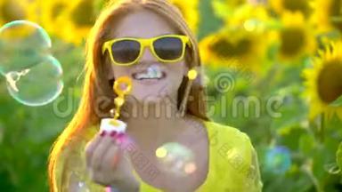 红长发的美女站在黄色的向日葵地上吹泡泡。快乐的女人在户外。青少年